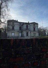 Die Frontansicht einer heruntergekommenen Villa mit zwei Stockwerken und großen Fenstern